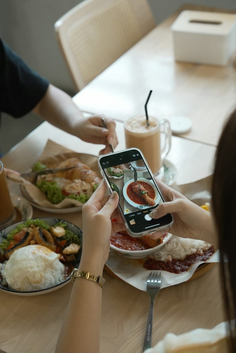 People taking photos of food at a cafe table.